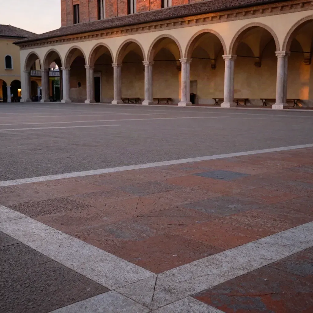 Piazza in terracotta dell’Emilia-Romagna con portici e torre di mattoni in alto.